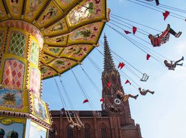 Colorful swing carousel in motion in front of a Gothic church