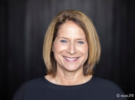 Portrait of a smiling woman with shoulder-length hair against dark backdrop