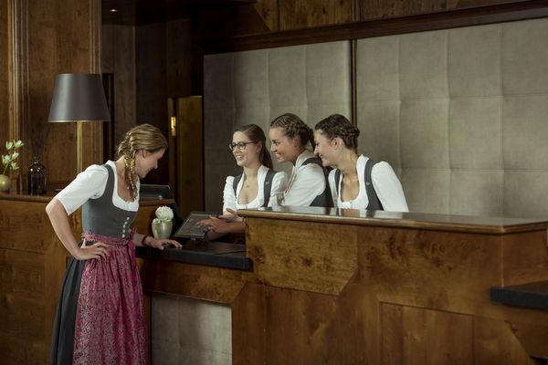 Four female employees of the Platzl Hotel in Munich are standing around the reception of the hotel and talking