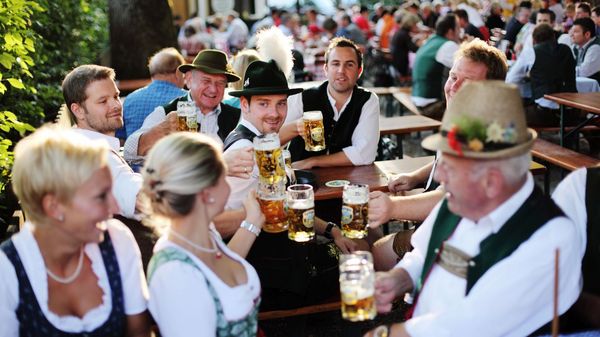 Eine Gruppe mehrerer Menschen in Tracht stoßt auf einem Fest mit Maßkrügen an