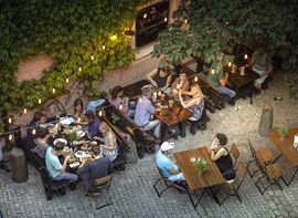 Aerial view of a cozy courtyard restaurant with guests dining under trees and lights