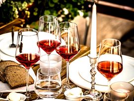 Set table with filled wine glasses, plates and bread.