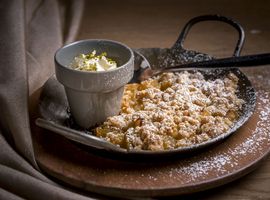 Nahaufnahme von Ayinger Apfelpfanderl mit Sahne und Puderzucker