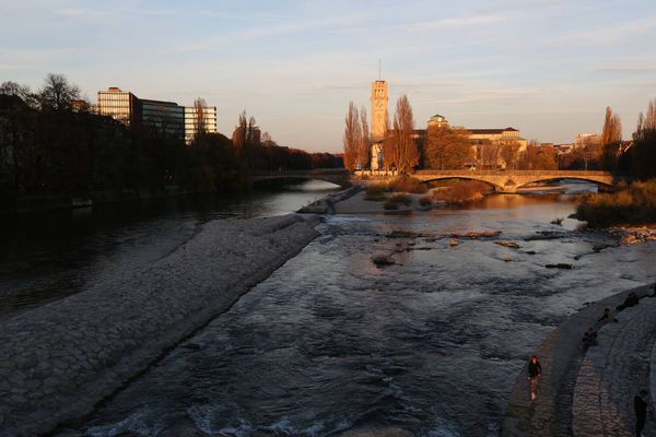 Die Isar in München bei Sonnenuntergang mit Blick auf das historische Müllersche Volksbad und die Ludwigsbrücke.