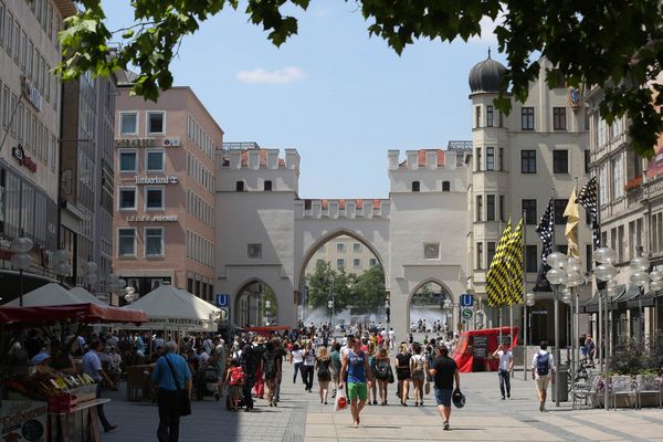 On a sunny day, visitors stroll through the bustling pedestrian zone under the famous Karlstor archway.