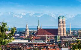 [Translate to Englisch:] Blick über die Münchner Altstadt mit den Türmen der Frauenkirche vor den Alpen im Hintergrund.