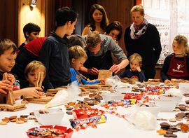 Children & young adults baking cookies with representatives of the Nicolaidis YoungWings Foundation.