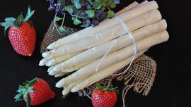 Bunch of white asparagus garnished with strawberries.