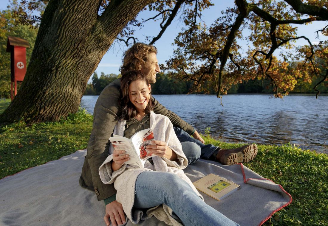 Young couple enjoying a drink by the lake in autumn atmosphere