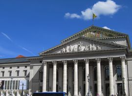 Ein neoklassizistisches Gebäude mit großen Säulen erhebt sich gegen den blauen Himmel.