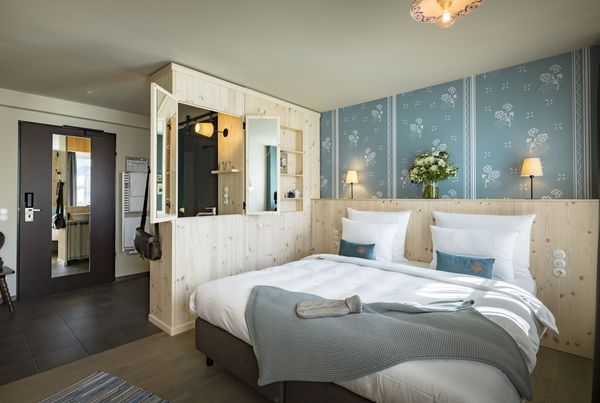 Vor einer dekorativen Wand steht ein großes Doppelbett im Marias Platzl Hotel