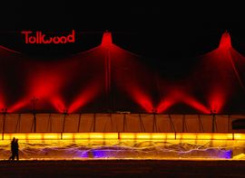 Zelt auf dem Tollwood Winterfestival bei Nacht, mit zwei vorbeischlendernden Personen.