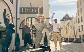Vier Azubis springen energetisch in die Luft vor dem Eingang des Platzl Hotel München