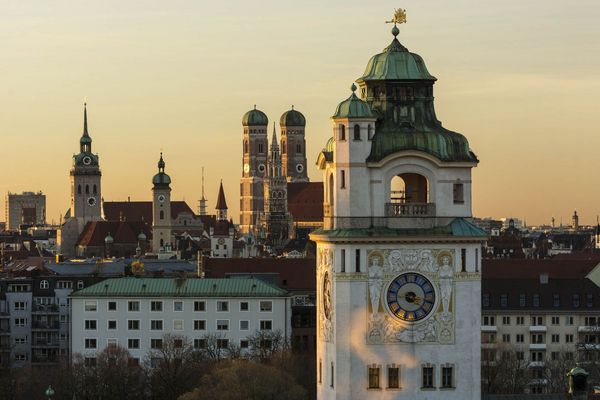 Überblick über die Dächer Münchens mit den verschiedenen Kirchtürmen im Sonnenuntergang.