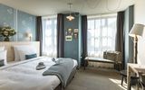 Großzügiges Doppelbett mit Wärmflasche und Kuscheldecke im Doppelzimmer Gundi des Boutique Hotel München