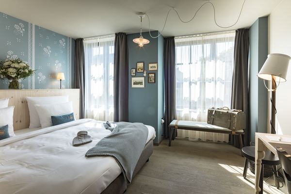 Großzügiges Doppelbett mit Wärmflasche und Kuscheldecke im Doppelzimmer Gundi des Boutique Hotel München