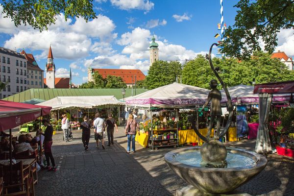 People browsing the colorful market stalls at Munich's Viktualienmarkt on a sunny day