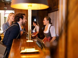 A young lady and a man are received with a smile by a receptionist
