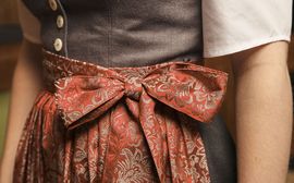 Traditionelles Dirndl mit einer rosa Schürze mit Schleife.